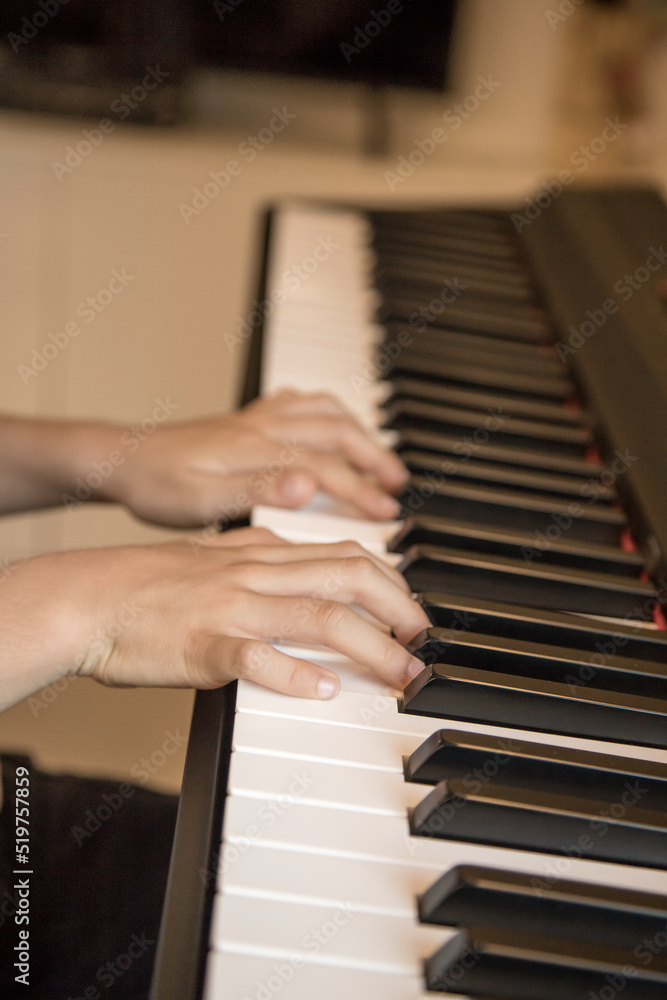 Hands of the child playing piano. Initiation to music, experiences and learning, concept. Closed image and shallow depth of field.