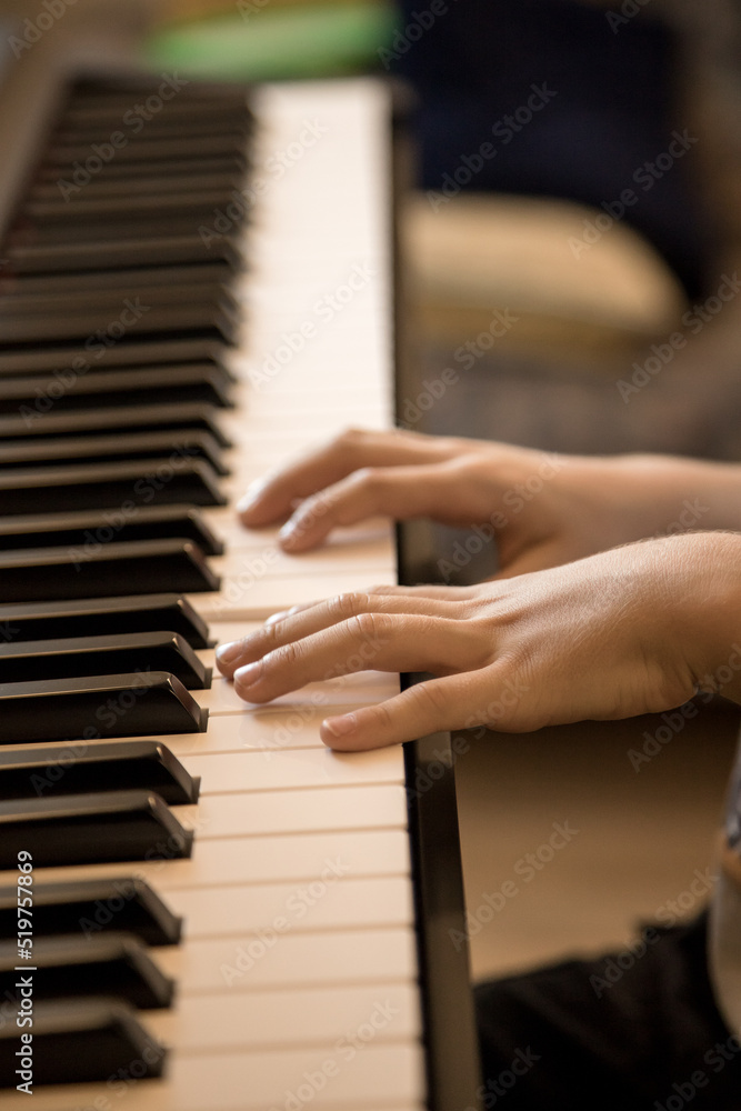 Hands of the child playing piano. Initiation to music, experiences and learning, concept. Closed image and shallow depth of field.