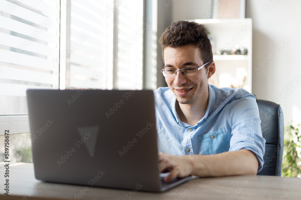 Happy young man in glasses with laptop computer working at home office. technology, remote job and lifestyle concept . Happy young man in glasses with laptop computer working at home office. technology, remote job and lifestyle concept .