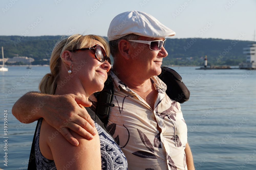 portrait of a smiling middle aged couple in sunglasses on the sea