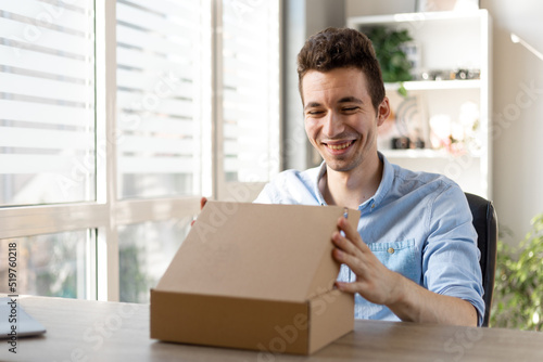 Excited caucasian man customer receive good parcel open cardboard box at home satisfied with great purchase, happy male consumer unpack package look inside overjoyed by postal shipping delivery.