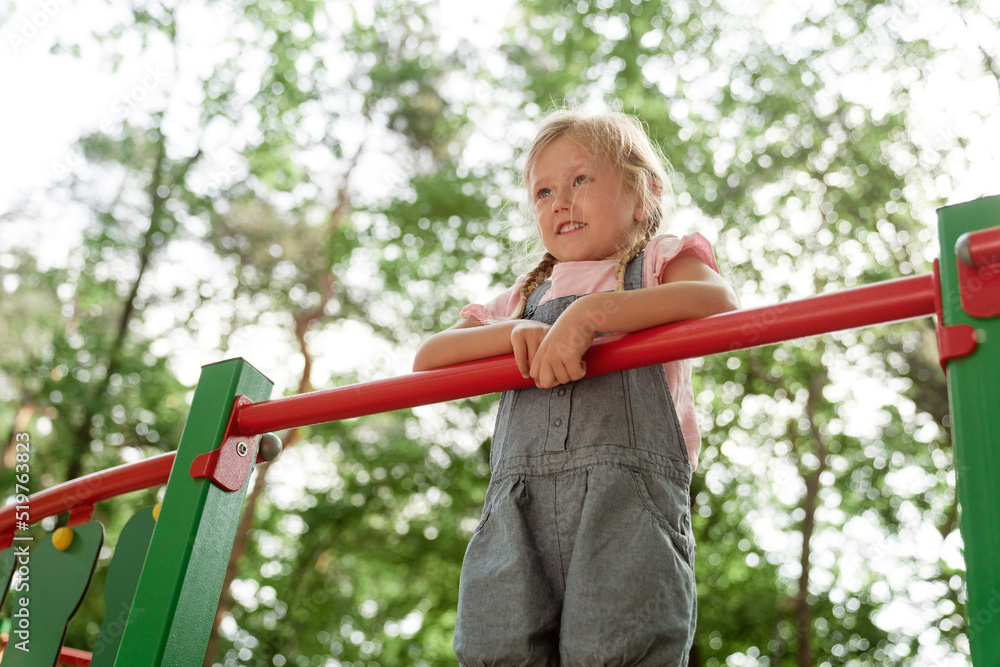 Obraz premium Little girl standing at the playground in summer day