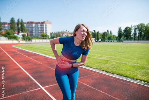 Girl in sportswear in stadium is exhausted and has pain during training and workout