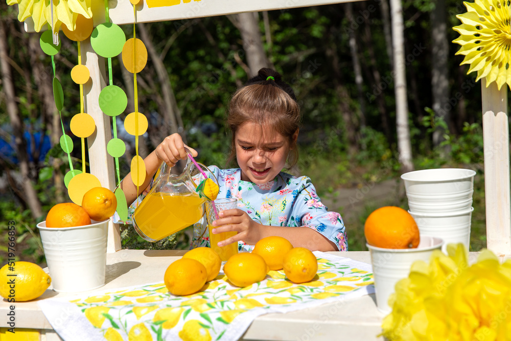 Pretty girl sells lemonade on the street in the park