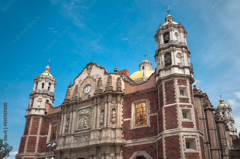 Facade view with double columns, stone carvings and niches with saint statues of the old restored Basilica of Our Lady of Guadalupe, Mexico City -Revered Catholic church and pilgrimage site in Mexico.