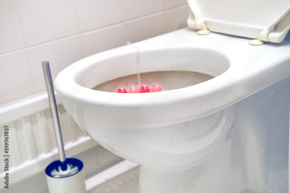 white faience toilet bowl, home toilet, disinfectant flavoring balls on