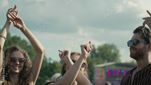 Young caucasian friends dancing on music festival with hands up. Shot with RED helium camera in 8K. 