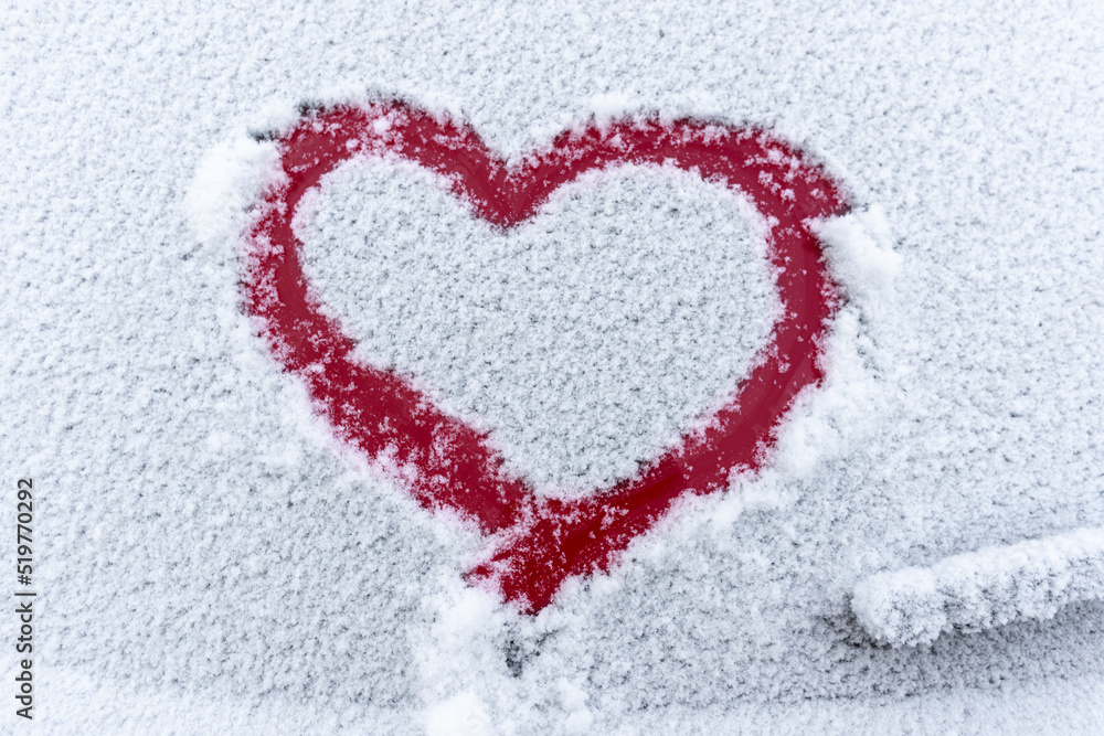 Snow red heart on the car window with copy space. Heart sign in fresh snowflakes. Heart shape symbol drawn on snowed car glass. Love concept. Valentine's Day. Declaration of love