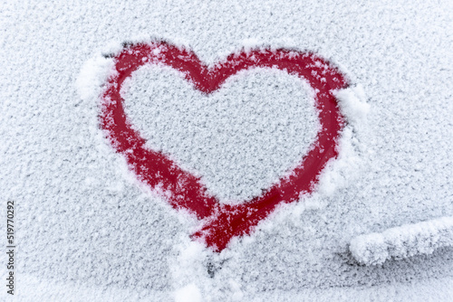 Snow red heart on the car window with copy space. Heart sign in fresh snowflakes. Heart shape symbol drawn on snowed car glass. Love concept. Valentine s Day. Declaration of love