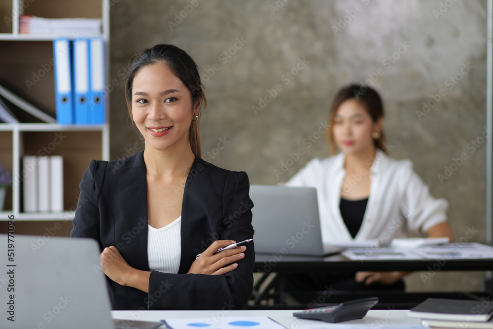 Portrait of a businesswoman or female manager working on a laptop in the office. Looking at camera. Portrait of a businesswoman or female manager working on a laptop in the office. Looking at camera.