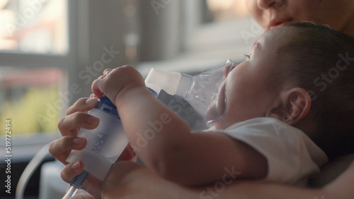 Side view of baby breathing an inhaler at home