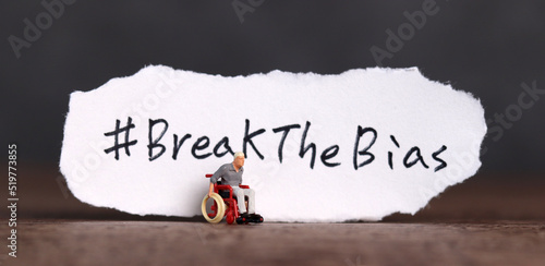 Torn paper with the word ‘BreakTheBias' written on it. Break the bias campaign with a miniature man in a wheelchair.
 photo