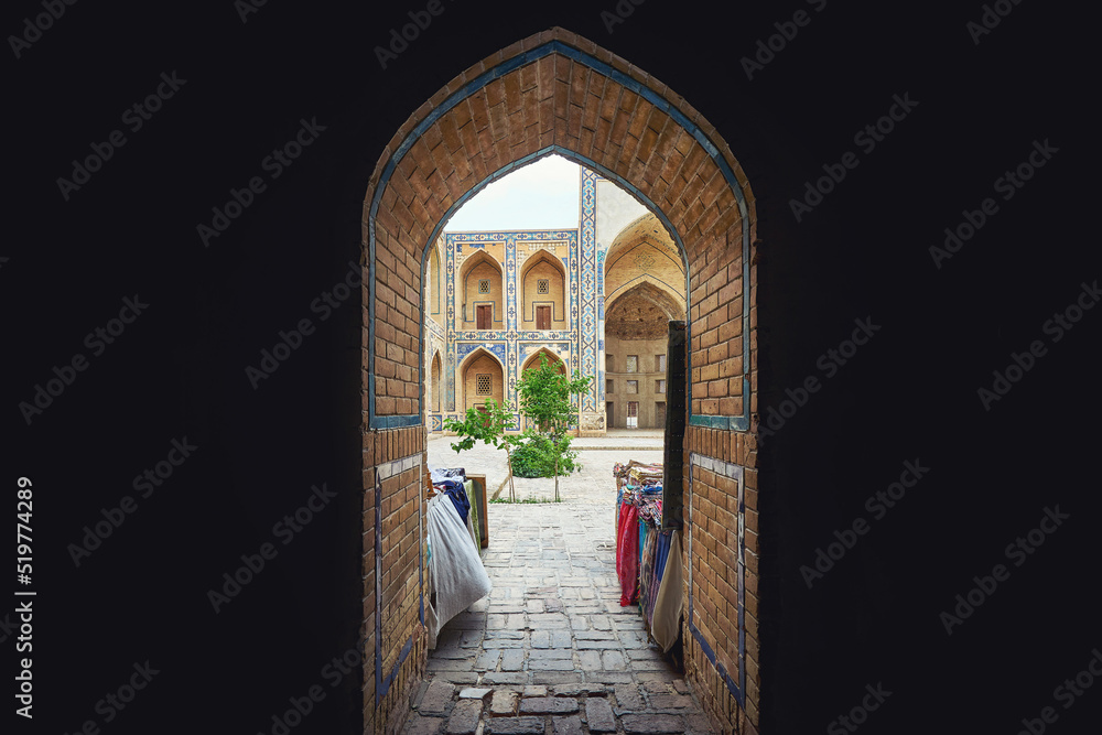 Fototapeta premium View at the old madrasa in Uzbekistan from the dark room trough the old door