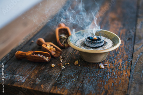 Incense burning on some coal - holy smoke ritual with different resins and herbs on a dark wooden rustic table photo
