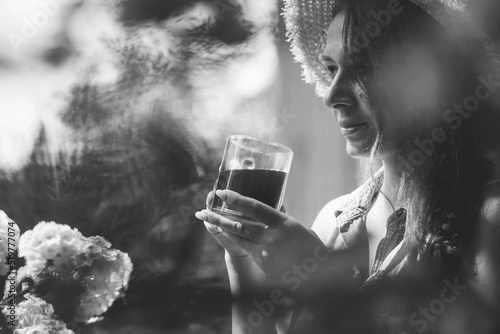 A beautiful young woman is happy and enjoys a coffee drink in the morning at the cottage. A girl holds a cup of coffee or tea outdoors. Relaxes the lifestyle. The concept of a good and early morning.