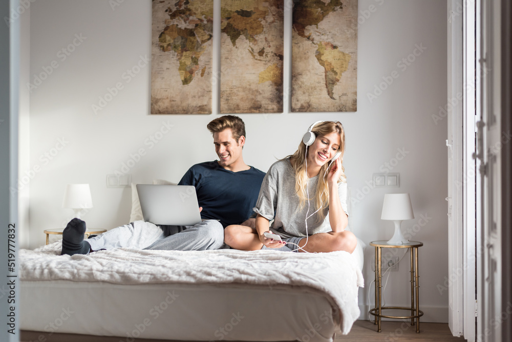 couple on bed entertained on the computer and listen to music couple on bed entertained on the computer and listen to music
