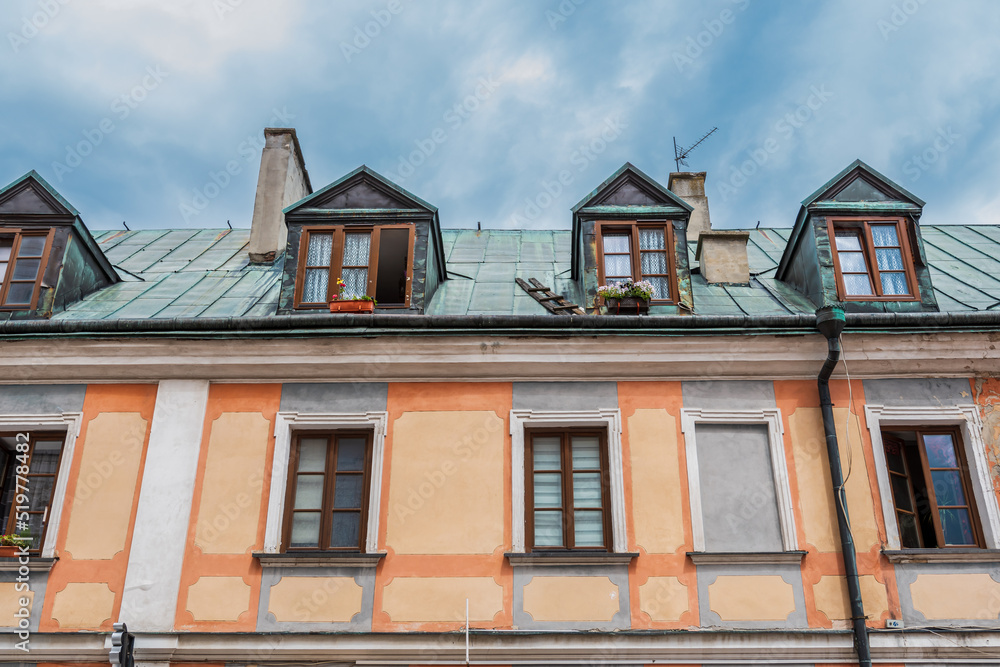 Fototapeta premium A beautiful, colorful, slightly dilapidated tenement house in the old town. The roof is covered with a zinc sheet. Zamosc, Poland