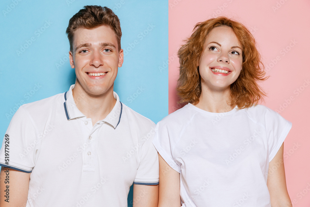 Portrait of beautiful young couple, man and woman smiling at camera, posing isolated over pink blue studio background Portrait of beautiful young couple, man and woman smiling at camera, posing isolated over pink blue studio background
