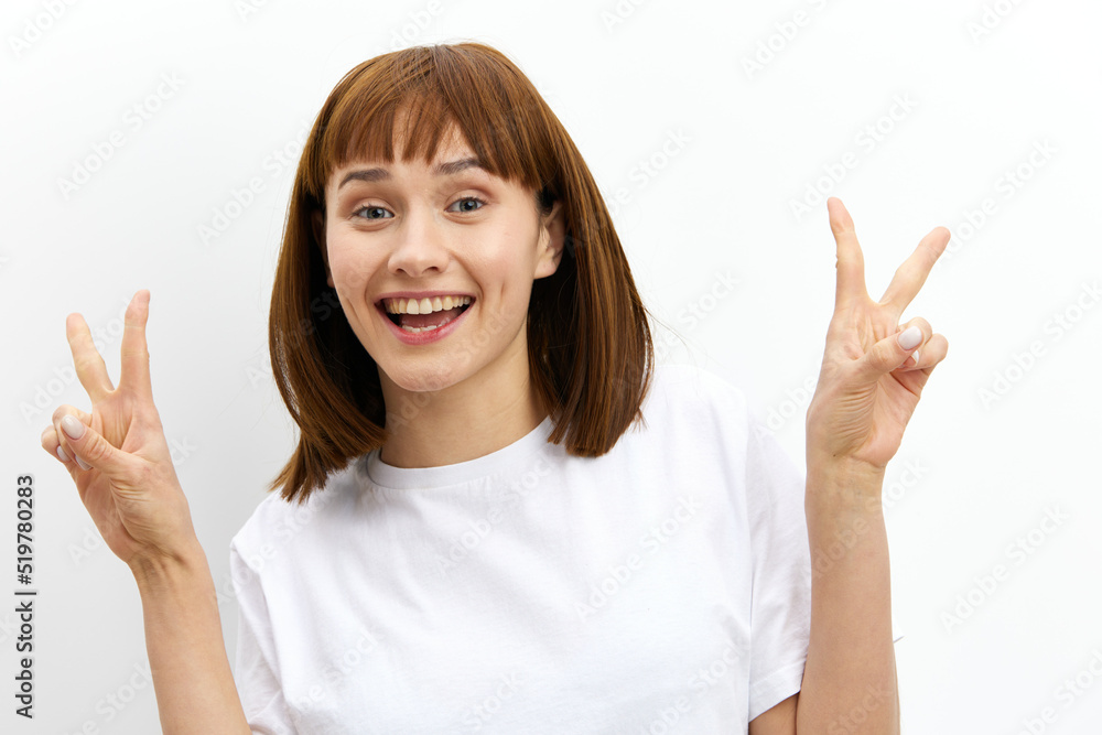 a happy, sweet, inspired red-haired woman stands on a white background in a white T-shirt and smiling pleasantly shows a heart sign with her hands. Horizontal studio photography with empty space a happy, sweet, inspired red-haired woman stands on a white background in a white T-shirt and smiling pleasantly shows a heart sign with her hands. Horizontal studio photography with empty space
