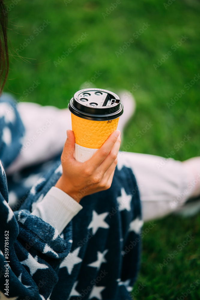 Woman's hand holding a paper glass of coffee in the park Woman's hand holding a paper glass of coffee in the park