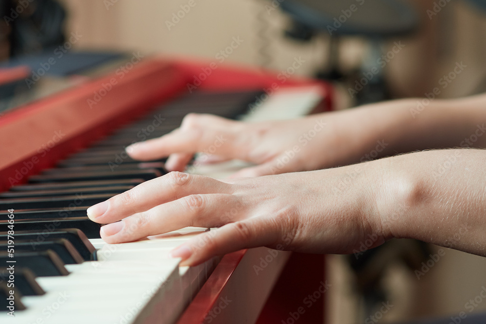 Obraz premium Close-up side view of a woman's hand playing a red electronic piano