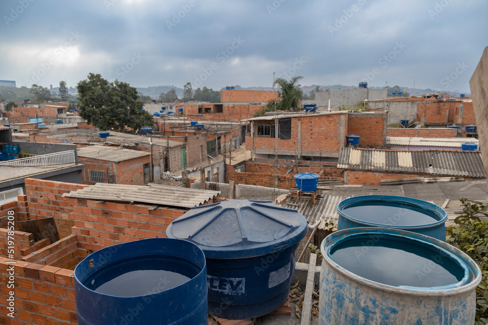 Naklejka premium Jardim Pantanal, São Paulo, SP, Brazil, JUL 27, 2022, Drums of water accumulated on the terrace of houses in the poor community