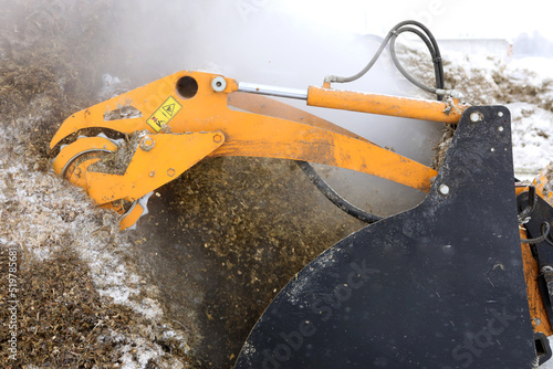 Bucket with Emily mobile cutter. Selection of silage and haylage from silage and haylage trenches. Fodder for animals in winter.