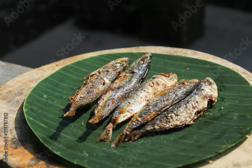 indonesian authentic food fried salted fish or ikan asin gereh on wooden surface with banana leaf. photo