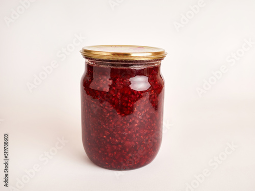 A jar of homemade canned raspberry jam. The concept of home preservation.