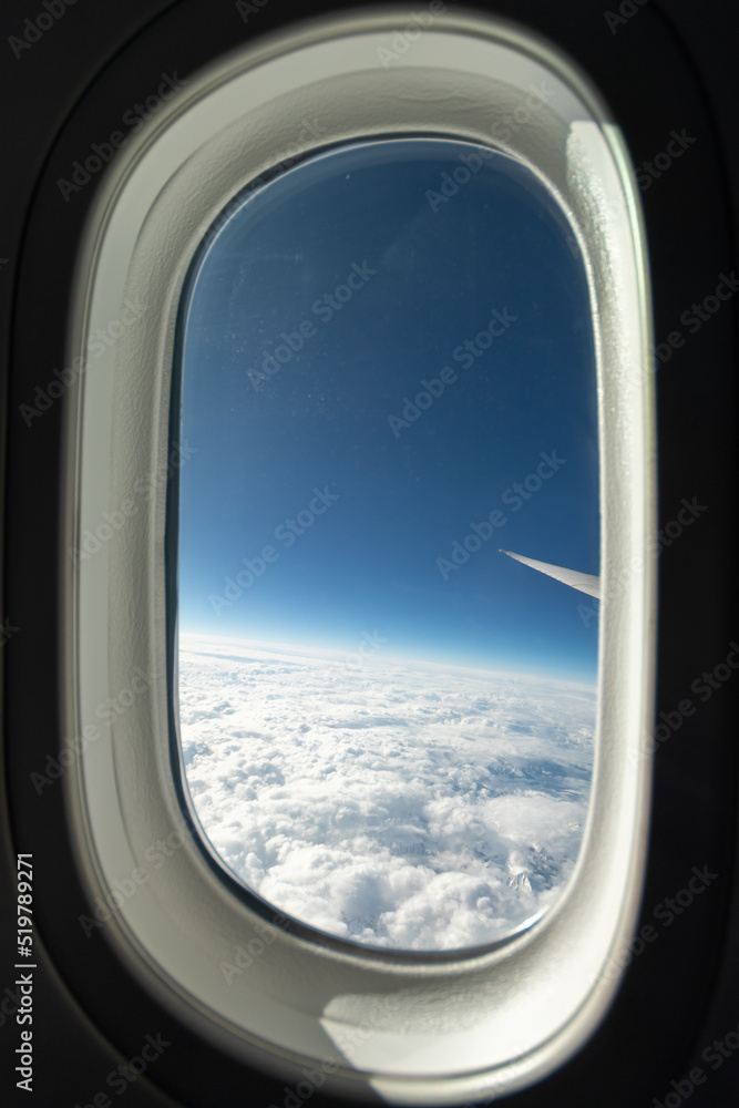 Full window view of a Boeing 787 in the sky on a clear day with mountains below. Full window view of a Boeing 787 in the sky on a clear day with mountains below.