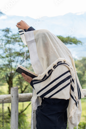Jew praying and reading the siddur while raising his right arm to heaven. photo
