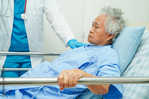 Asian elder senior woman patient holding bed rail while lie down with hope waiting her family in hospital.
