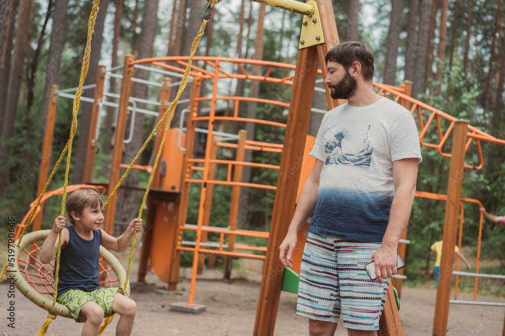 cute little boy having fun on a swing at playground. cute little boy having fun on a swing at playground.