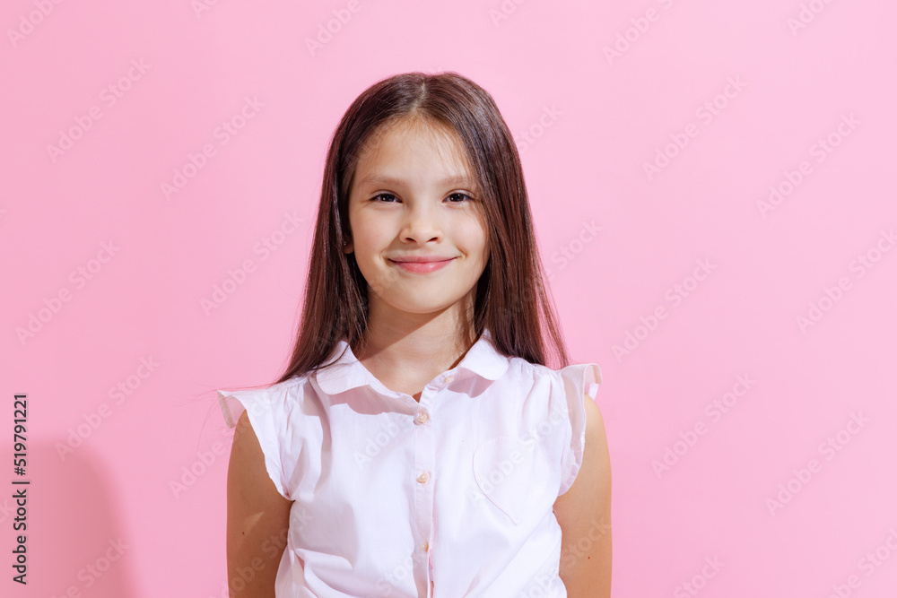 Smiling school age charming girl, kid wearing blouse isolated on pink background. Concept of children emotions, fashion, beauty, school and ad Smiling school age charming girl, kid wearing blouse isolated on pink background. Concept of children emotions, fashion, beauty, school and ad