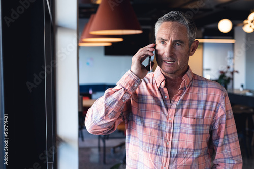 Caucasian mature businessman talking on mobile phone in creative office