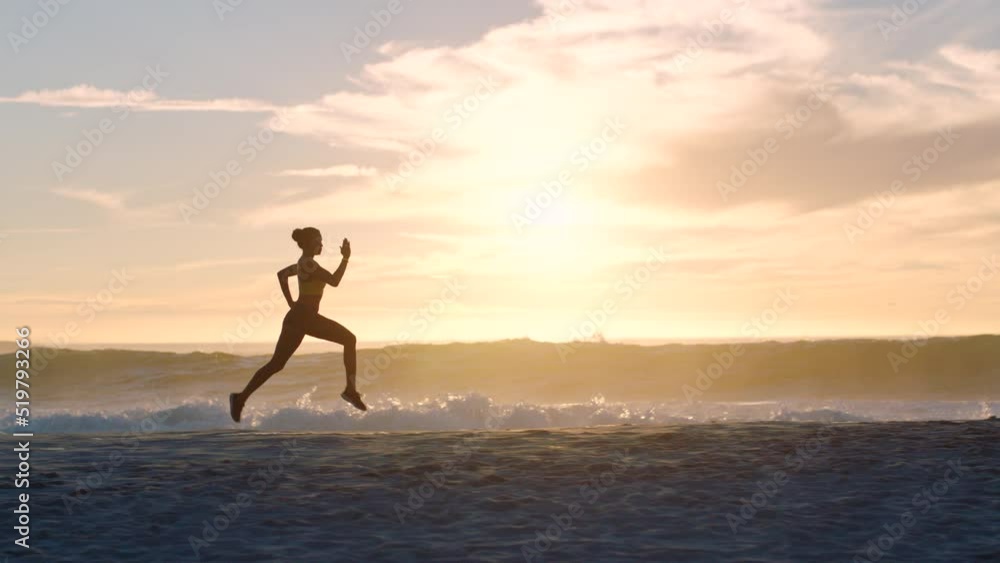 Active, fit and sporty athlete running on beach shore with waves, sunset background and copy space. Shadow, outline and silhouette of a healthy woman with stamina doing workout, exercise and training Active, fit and sporty athlete running on beach shore with waves, sunset background and copy space. Shadow, outline and silhouette of a healthy woman with stamina doing workout, exercise and training