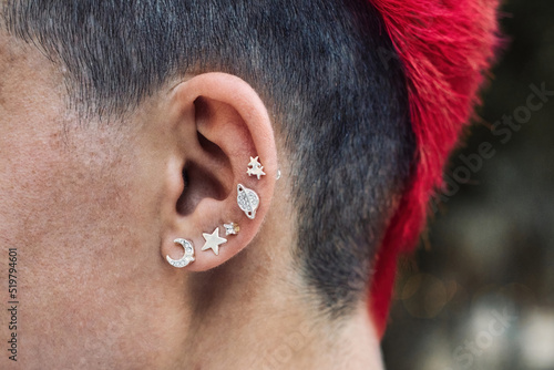Closeup of a female punk's ear with silver piercings and a bright red dyed mohawk personal hair style photo