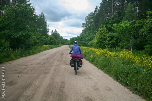 Fototapeta Naklejka Na Ścianę i Meble -  A tourist on a bicycle rides along the road among the blooming fields of Bashkiria, Russia.