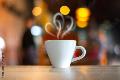 Hot Coffee Cup on Wood Table in blurred Coffee Shop background.