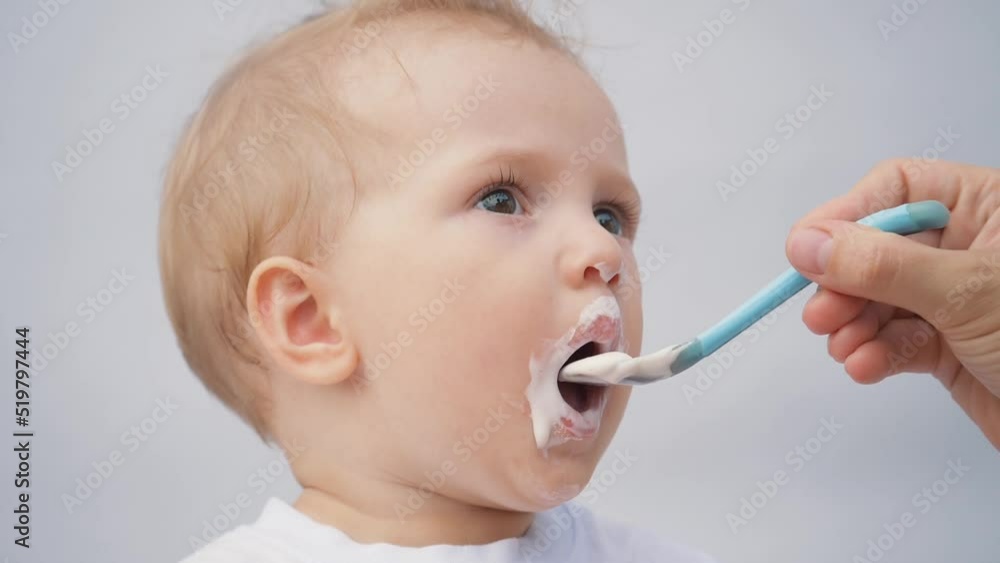 happy, caring mother spoon-feeds her baby. porridge. Spoon-feeding children with baby food. Caring childcare. Happy kid eating porridge from a spoon. The baby's face is porridge. happy, caring mother spoon-feeds her baby. porridge. Spoon-feeding children with baby food. Caring childcare. Happy kid eating porridge from a spoon. The baby's face is porridge.