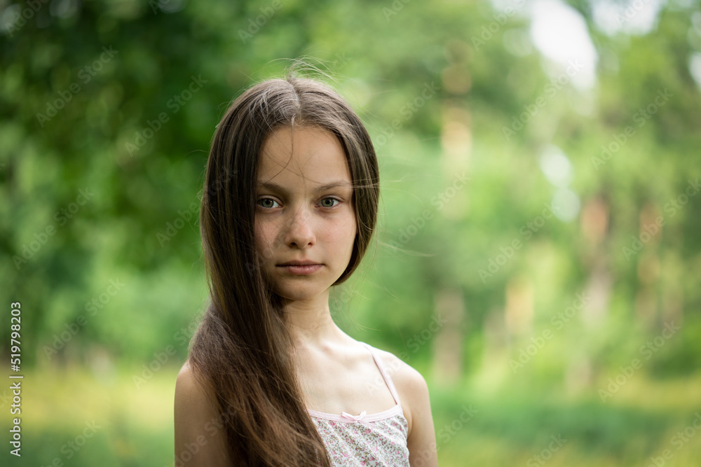 Portrait of beautiful preteen girl in forest on summer sunny day