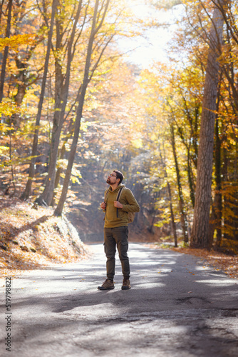 Young handsome man posing in autumn forest. young hipster guy with backpack , traveller standing in woods, Hiking, Forest, Journey, active healthy lifestyle, adventure, vacation concept. © YURII Seleznov