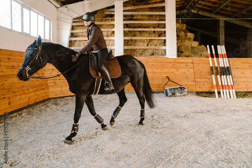 Jockey woman wearing helmet riding her horse during equestrian practice