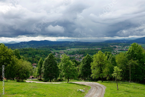 Beautiful view macadam path and hilly countryside with rolling gray storm clouds