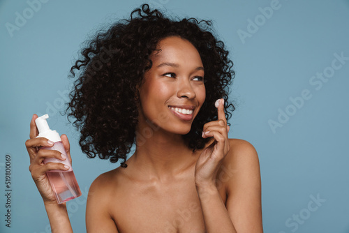 Black shirtless woman smiling and using cleaning foam