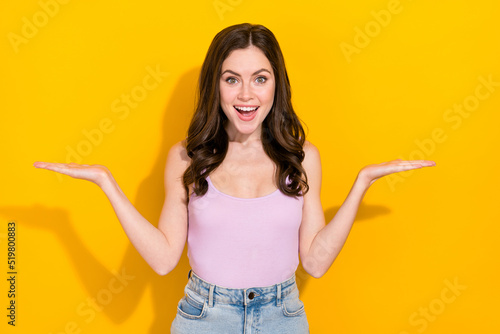 Photo of shocked cheerful lady arms palms hold demonstrate empty space vs scales isolated on yellow color background
