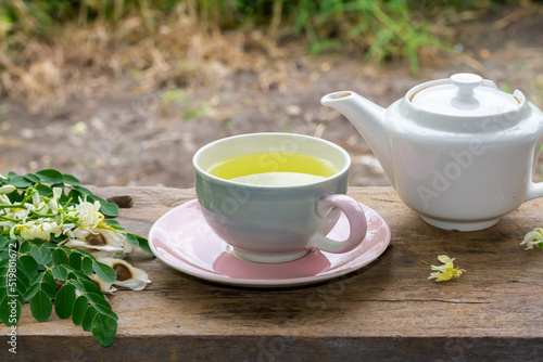 Moringa Tea in cup and fresh green leaf  flower and seeds with teapot on wooden  blur background.  Moringa oleifera tropical herb healthy lifestyle concept.