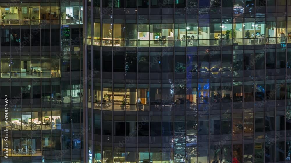 Big glowing windows in modern office and residential buildings timelapse at night, in rows of windows light shines. Skyscrapers in financial district