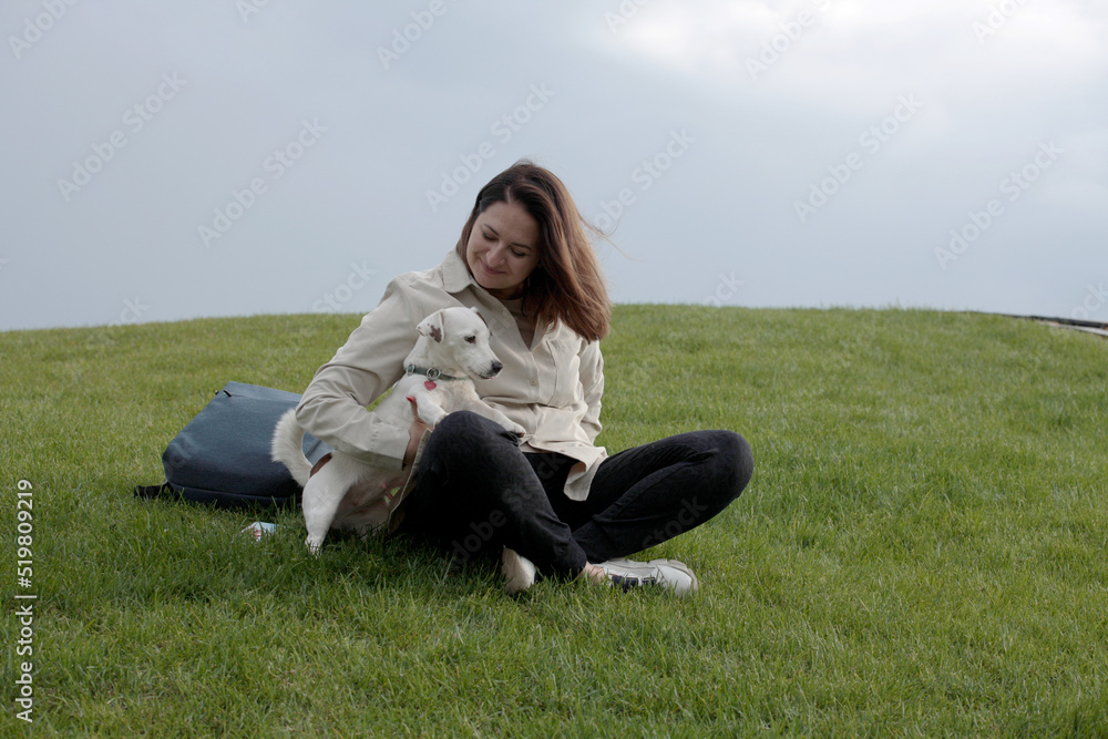 Girl gives tasty patches of dog treats to a white dog on the background of the sky Girl gives tasty patches of dog treats to a white dog on the background of the sky
