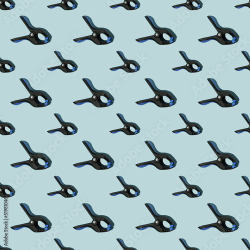 Seamless pattern of black multipurpose clamps with blue grips. Blue background.